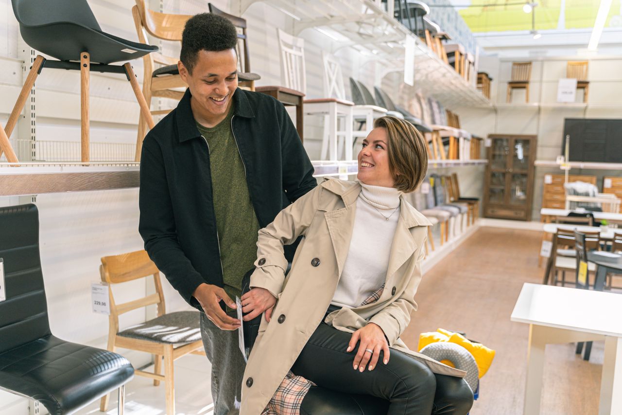 A couple happily explores a furniture store filled with stylish chairs and decor, showcasing modern lifestyle.